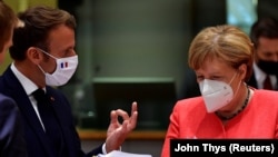 អធិការបតីអាល្លឺម៉ង់ លោកស្រី Angela Merkel ពិនិត្យ​មើល​ឯកសារ​ ខណៈ​ដែល​ប្រធានាធិបតី​បារាំង Emmanuel Macron និយាយ នៅឯ​កិច្ច​​ប្រជុំ​កំពូល​ទល់​មុខ​គ្នា នៅ​ទីក្រុង​ប្រ៊ុចសែល ប្រទេស​ប៊ែលហ្ស៊ិក កាល​ពី​ថ្ងៃ​ទី​២០ កក្កដា ២០២០។