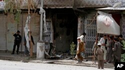 People gather after clashes between Afghan forces and Taliban fighters, in which police shot dead two would-be suicide bombers. Two others blew themselves up in Kandahar, southern Kabul, Afghanistan, June 15, 2014. 