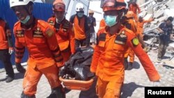 Tim SAR membawa korban dari reruntuhan Hotel Roa-Roa di Palu, Sulawesi Tengah, 30 September 2018.