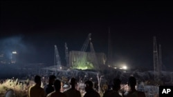 People look at the scene of Tuesday's explosion that hit the seaport of Beirut, Lebanon, Aug. 7, 2020.