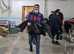A member of the Syrian Violet Organization carries an injured boy at a makeshift hospital following a government airstrike on a vegetable market in Syria's last major opposition bastion of Idlib, Jan. 15, 2020.