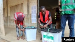 Des agents électoraux scellent des urnes vides devant un bureau de vote avant l'ouverture de celui-ci pour les élections législatives et régionales du Togo, à Lomé, Togo, le 29 avril 2024. 