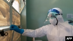 FILE - A medical staff member wears protective equipment while closing a window at the Wilkins Infectious Diseases Hospital in Harare, March 11, 2020.