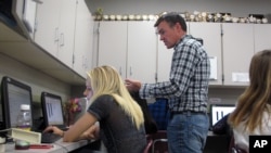 West Fargo High School journalism teacher Jeremy Murphy talks with senior Elizabeth Ratchenski, left, during a publications class on Friday, Aug. 28, 2015, in West Fargo, N.D. Journalism students returning to West Fargo and other North Dakota public schools last year were able to do their jobs at high school and college newspapers with stronger free-speech protections under state law. (AP Photo/Dave Kolpack)