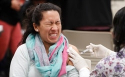 A women reacts to getting an influenza vaccine shot at Eastfield College in Mesquite, Texas, Jan. 23, 2020.
