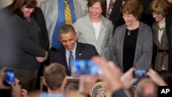 President Barack Obama signs a Presidential Memorandum to modernize overtime protections, in the East Room of the White House in Washington, Mar. 13, 2014. 