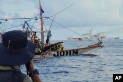 Kapal Penjaga Pantai Tiongkok melewati perahu aktivis dan sukarelawan dari koalisi non-pemerintah bernama Atin Ito, bahasa Tagalog untuk This is Ours, di Laut Cina Selatan pada Kamis 16 Mei 2024. (Foto: via AP)