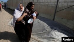 Warga Palestina meninggalkan rumah mereka setelah serangan udara yang dilancarkan oleh Israel di sebuah rumah di Khan Younis, Jalur Gaza selatan, 30 Juli 2014.