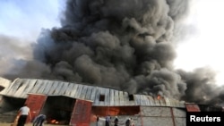 Para petugas pemadam kebakaran berusaha memadamkan kebakaran yang melanda gudang yang dipakai oleh Program Pangan PBB (WFP) di Hodeida, Yaman. 