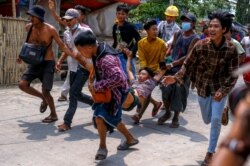 Protesters carry an injured man after riot policemen and soldiers shot rubber bullets during a crackdown on demonstrations in Yangon, Myanmar, March 14, 2021.