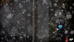 សន្តិសុខ​ម្នាក់​ពាក់​ម៉ាស់​នៅ​ពេល​លោក​ឈរ​យាម​នៅ​ពេល​មាន​ព្រិល​ធ្លាក់​នៅ​ក្នុង​ក្រុង​ប៉េកាំង កាលពី​ថ្ងៃទី១៤​ ខែកុម្ភៈ ឆ្នាំ២០២០។