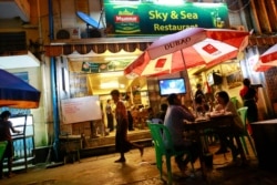 FILE - People eat at a restaurant along a street in Yangon, Myanmar, Aug. 18, 2013.