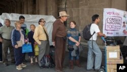 FILE - Voters stand in line in Mexico City, Nov. 24, 2018, to cast their decision on the referendum regarding the construction of the so called "Mayan Train," that would connect several cities of the Yucatan peninsula. 