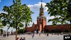A picture taken on May 25, 2021 shows people wearing protective face masks against the coronavirus, Covid-19, as they rest in Red Square in Moscow. (Photo by Dimitar DILKOFF / AFP)