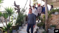 In this photo released on Friday, Dec. 29, 2017 by the official Facebook page of the Syrian Presidency, Syrian President Bashar Assad with members of the first family, visit wounded veterans at their houses over the holidays, in the central province of Homs, Syria. 