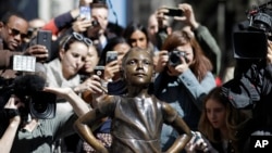 Orang-orang berkerumun untuk memotret patung Anak Perempuan Pemberani di New York (8/3). (AP/Mark Lennihan)