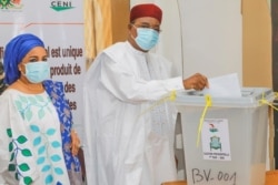 Incumbent President Mahamadou Issoufou, pictured with his wife, Aissata Issoufou Mahamadou, casts his vote in Niamey, Dec. 27, 2020. (Mahmud Lalo/VOA Hausa)