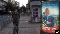 A man walks by an election poster of pro-Western Prime Minister Milo Djukanovic, leader of the Democratic Party of Socialists, reading "We are joining NATO, we are at the doorstep at the developed European family" and "With firm step ahead!" in downtown Podgorica, Montenegro, Oct. 12, 2016.