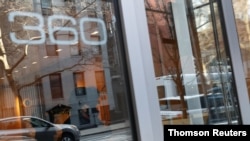 A woman leaves 360 West 43rd street as security and a doorman stand inside the building, where a man has now been charged with assaulting a 65-year-old Asian woman in a hate crime, where the incident was reported, in New York City, April 1, 2021.