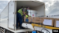 មន្ត្រី​សុខាភិបាល​ស៊ីមបាវ៉េ​ម្នាក់​ជញ្ជូន​វ៉ាក់សាំង​បង្ការ​ជំងឺ​កូវីដ១៩ Sinopharm ចេញ​ពី​យន្ដហោះ​មួយ​គ្រឿង​ដែល​ដឹក​មក​ពី​ចិន ទៅ​ក្នុង​រថយន្ដ​ដឹកទំនិញ​របស់​រដ្ឋាភិបាល​ស៊ីមបាវ៉េ នៅ​អាកាសយានដ្ឋាន​អន្តរជាតិ Robert Gabriel Mugabe ថ្ងៃទី១៥ ខែកុម្ភៈ ឆ្នាំ២០២១។