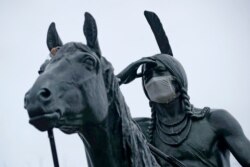 A statue of a Sioux Indian scout wears a face mask as it stands on a bluff overlooking Kansas City, Mo., March 26, 2020.