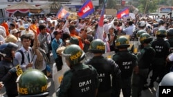 Cambodian riot police officers block protesters led by Cambodia's most prominent human rights defender Mam Sonando demanding the government to allow him to open a new television channel in Phnom Penh, Cambodia, Monday, Jan. 27, 2014. 