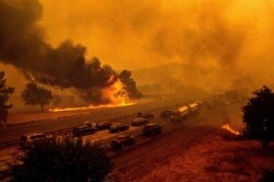 Flames from the LNU Lightning Complex fires jump Interstate 80 in Vacaville, Calif., Aug. 19, 2020. The highway was closed in both directions shortly afterward.