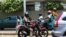 Un conducteur de moto remorquant 3 passagers à Lomé, le 14 août 2019. (VOA/Kayi Lawson)