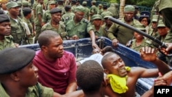 FILE - Zambian police officers apprehend supporters of the opposition United Party for National Development outside the presidential election result center at the Mulungushi International Conference Center in Lusaka, Jan. 21, 2015.