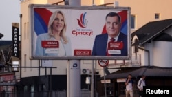 People walk next to a pre-election billboard showing Milorad Dodik and Zeljka Cvijanovic of the Alliance of Independent Social Democrats (SNSD) in Gradiska
