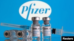 Botol berlabel 'Vaksin Coronavirus COVID-19' dan jarum suntik terlihat di depan logo Pfizer dalam ilustrasi ini yang diambil 9 Februari 2021. (Foto: Reuters)