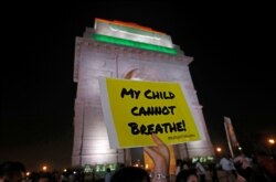 FILE - A protester holds a placard in front of the India Gate during a protest demanding government action to control air pollution, in New Delhi, India, Nov. 5, 2019.