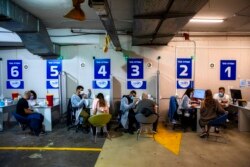FILE - Israelis receive a Pfizer-BioNTech COVID-19 vaccine from medical professionals at a coronavirus vaccination center set up on a shopping mall parking lot in Givataim, Israel, Feb. 4, 2021.
