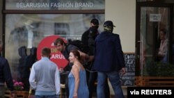 FILE - Unidentified men wearing face coverings detain a man near a cafe during an opposition rally challenging presidential election results in Minsk, Belarus, Sept. 6, 2020. (Tut.By via Reuters) 