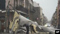 A man passes by a section of roof that was blown off of a building in the French Quarter by Hurricane Ida winds, Sunday, Aug. 29, 2021, in New Orleans. (AP Photo/Eric Gay)