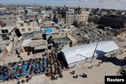 Warga Palestina melaksanakan salat Jumat pertama selama Ramadan di dekat reruntuhan masjid yang hancur, di Rafah, selatan Jalur Gaza, 15 Maret 2024. (Foto: REUTERS/Mohammed Salem)