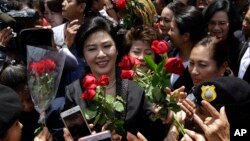 FILE - Thailand's former Prime Minister Yingluck Shinawatra, center, receives flowers from her supporters at the Supreme Court after making her final statements in a trial on a charge of criminal negligence in Bangkok, Thailand, Aug. 1, 2017. 