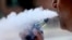 FILE - A man exhales while smoking an e-cigarette in Portland, Maine, Aug. 28, 2019. 