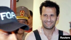 FILE - Lebanese-born businessman Assad Ahmad Barakat, a suspected member and fundraiser of the Islamic group Hizbollah, leaves the Justice building under escort of police officers in Asuncion, Nov. 18, 2003. 