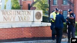 An officer (R) checks an ID outside of the Washington Navy Yard in the U.S. capital on September 17, 2013.