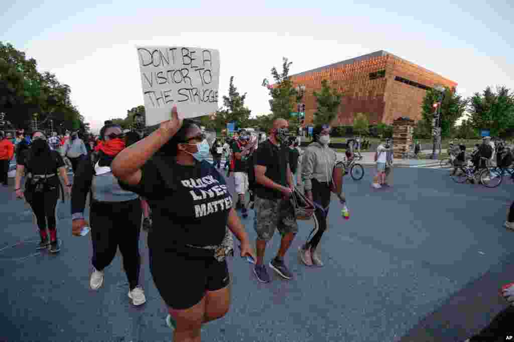 Demonstrators walk past the Smithsonian National Museum of African American History and Culture at they protest the death of George Floyd, May 31, 2020, in Washington. 