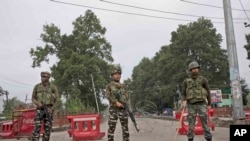 Indian paramilitary soldiers stand guard near a temporary check post on the road leading towards Independence Day parade venue during lockdown in Srinagar, Indian controlled Kashmir, Aug. 15, 2019.
