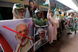 Women hold crossed out portrait of Indian Prime Minister Narendra Modi as they participate in a train march to mark the first anniversary of India's decision to revoke the disputed region's semi-autonomy, in Karachi, Pakistan, Aug. 5, 2020.