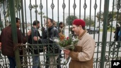 Seorang pria Tunisia menyerahkan bunga di pintu masuk Museum Nasional Bardo di Tunis, 21 Maret 2015. 