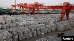  Workers ride on an motor rickshaw through an aluminium ingots depot in Wuxi, Jiangsu province.