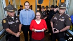Flanked by Rowan County Sheriff's deputies, Rowan County Clerk Kim Davis, center, with her son Nathan Davis standing by her side, makes a statement to the media at the front door of the Rowan County Judicial Center in Morehead, Kentucky, Sept. 14, 2015.