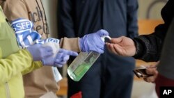FILE - In this March 27, 2020 photo, a patient arriving to pick up medication for opioid addiction is given hand sanitizer at a clinic in Olympia, Wash., that is currently meeting patients outdoors.