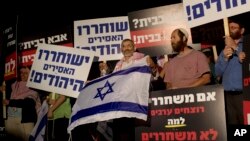 FILE - Israeli politician Michael Ben Ari, center, holds an Israeli flag while attending a demonstration against the release of Palestinian prisoners from Israeli jails, outside the Ofer military prison near the West Bank city of Ramallah, Oct. 29, 2013. 