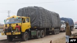 Pakistani drivers sit on the bumper of a loaded truck parked with other trucks along a road near the Wagah border between Pakistan and India on Feb. 20, 2019.