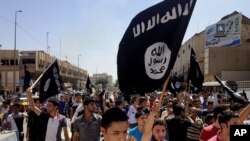 In this June 16, 2014 file photo, demonstrators chant pro-Islamic State group slogans as they carry the group's flags in front of the provincial government headquarters in Mosul, Iraq.